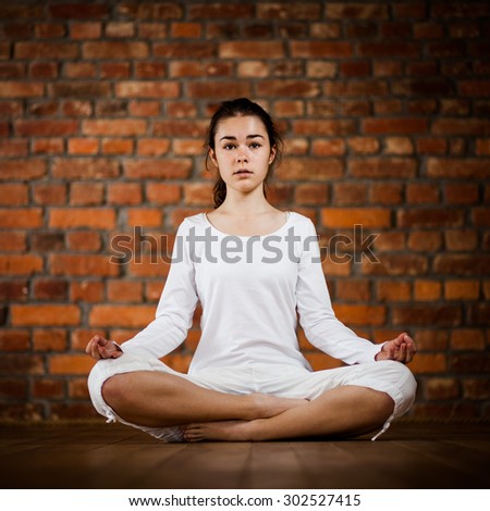 Woman exercising yoga against brick wall