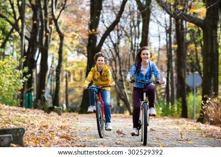 Urban biking - girl and boy riding bikes in city park