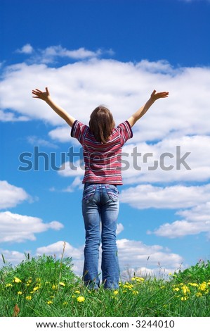 girl holding arms up in praise against blue sky
