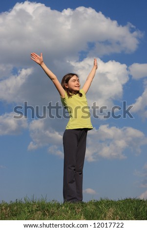 Girl holding arms up in praise against blue sky