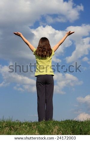 Girl holding arms up against blue sky