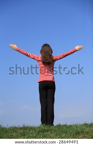 Girl holding arms up against blue sky
