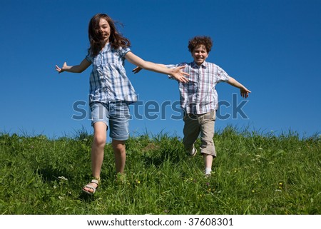 Kids running, jumping outdoor against blue sky