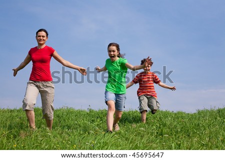 Active family - mother with kids running on green meadow