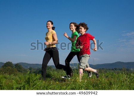 Active family - mother with kids running on green meadow