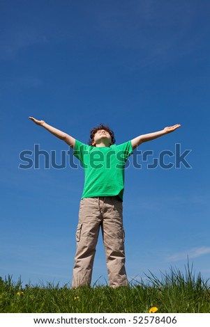 Boy holding arms up against blue sky