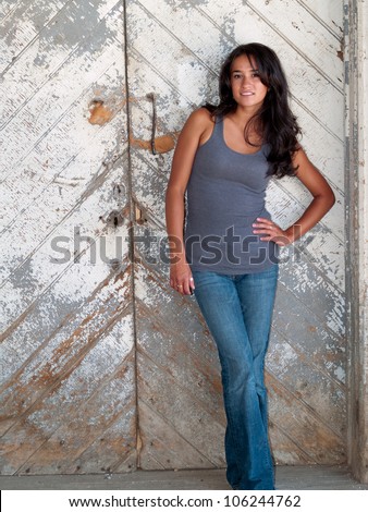 Young native american woman standing in front of a wooden door.