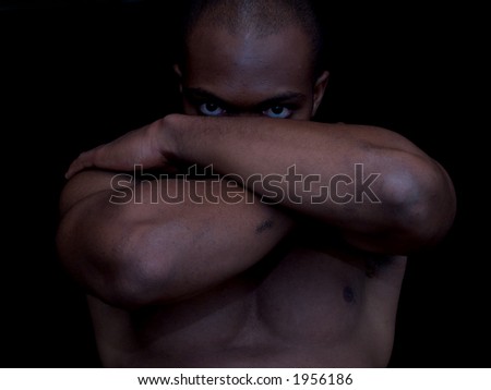 An african american man, arms crossed, eyes forward.