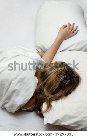 Girl is sleeping on white bed. Flower on a pillow next to her.