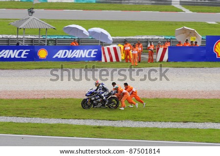 SEPANG, MALAYSIA - OCTOBER 21: Marshals assist MotoGP rider Katsuyuki Nakasuga after he crashed at the free practice session at the Shell Advance Malaysian GP 2011 on Oct 21, 2011 at Sepang, Malaysia