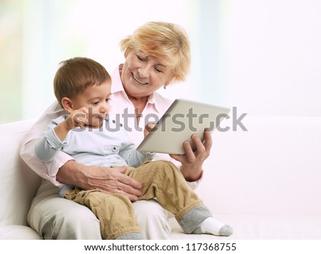 Grandmother reading a tale to her grandson from a digital tablet