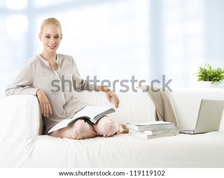 Young woman studying/ working at home with laptop on couch