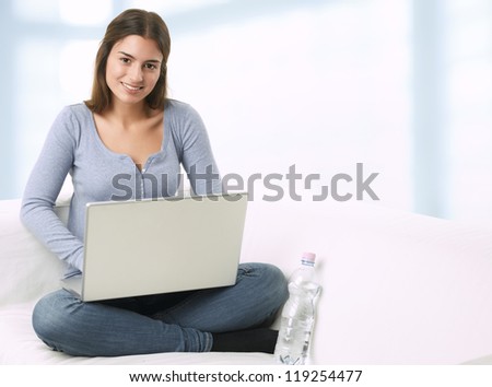 young woman sitting on couch with laptop and studying at home