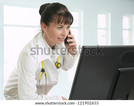 Female doctor talking on telephone and looking at the computer monitor