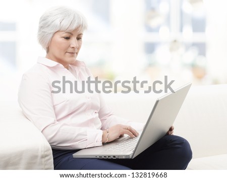 Portrait of a smiling senior woman working on laptop