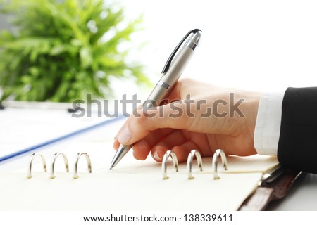 Close-up of female hand holding a pen and writing some research notes in the appointment book