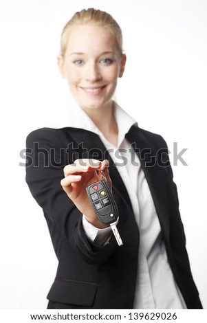 Rent a car! Smiling businesswoman giving car key. Isolated on white (focused on key)