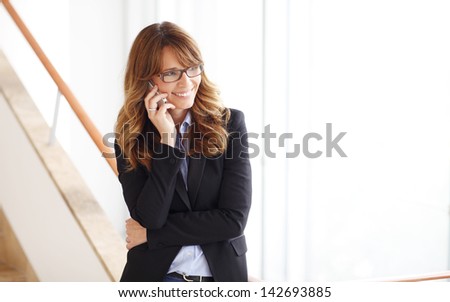 Modern lawyer businesswoman stands on set of steps in courthouse and talking on mobile phone