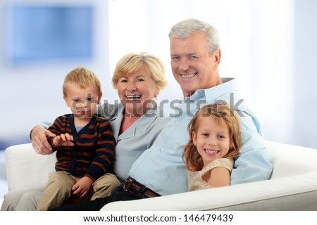 Portrait Of Grandparents With Grandchildren Relaxing Together On Sofa at Home