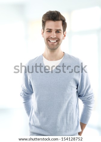 Portrait of smiling young man standing against white background