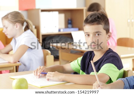 A group of children sitting in the classroom and writing