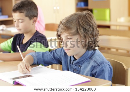 A group of children sitting in the classroom and writing