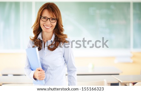 Smiling Teacher Standing In Front Of Blackboard