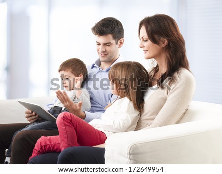 Happy family sitting on sofa in living room.