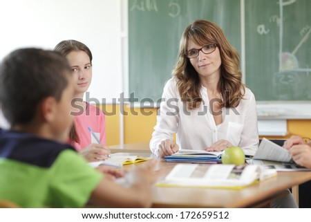 Elementary classroom setting. Focus on teacher and chalkboard.