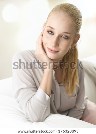 Beautiful young woman sitting on sofa in living room.
