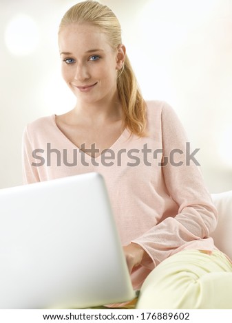 Beautiful young woman sitting on sofa in living room. White background.