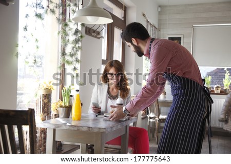 Small business owner serving coffee and cookies in coffee shop.