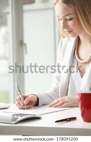 Beautiful businesswoman sitting at desk and fill the form.