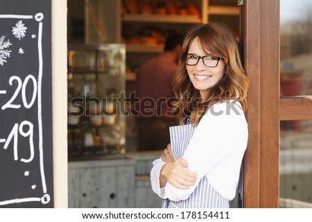 Small coffee shop owner standing in front of store.