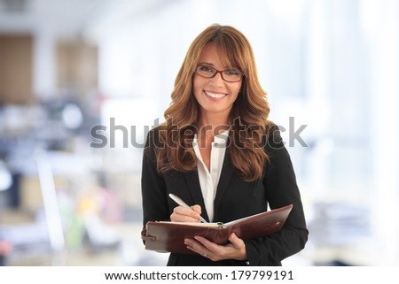 Portrait of mature businesswoman standing and making a list in her office.