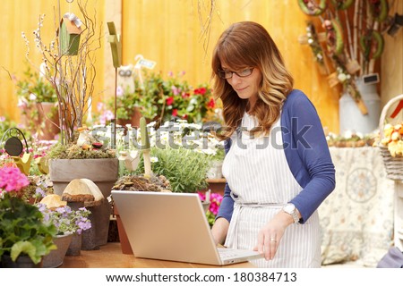Small flower shop owner working on laptop in her shop.