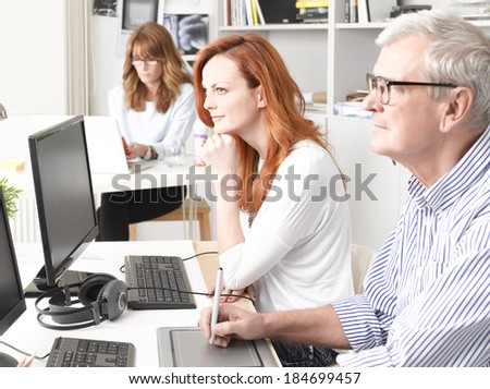 Graphic designer woman sitting at desk and working together with colleagues. Small business.