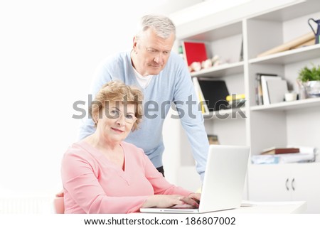 Happy senior couple sitting at desk and planning for retirement at home.