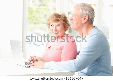 Happy senior couple sitting at desk and planning for retirement at home.