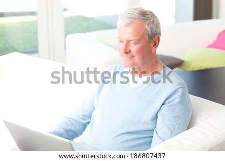 Portrait of active senior businessman sitting and working on computer. Small business.