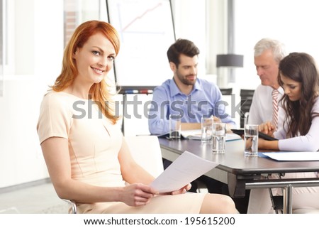 Beautiful executive businesswoman sitting at desk and smiling. Teamwork.