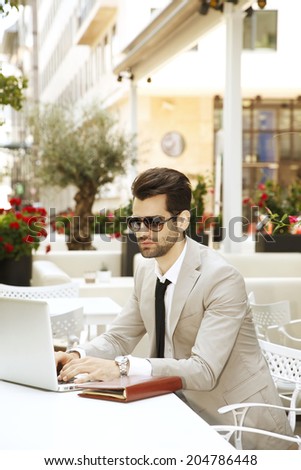 Modern young businessman analyze financial data, while sitting in coffee shop. Small business.