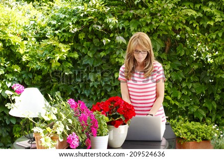 Portrait of small flower shop owner using laptop to take orders for her store. Business people.