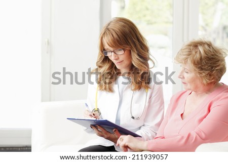 Female doctor consulting with senior patient at private clinic.