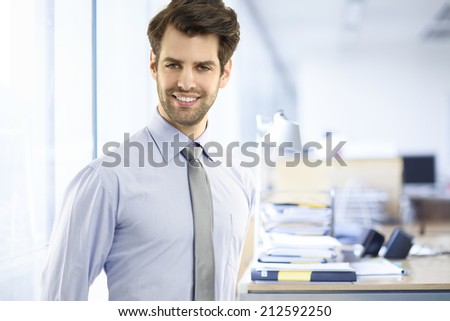 Portrait of young businessman standing at office. Small business.