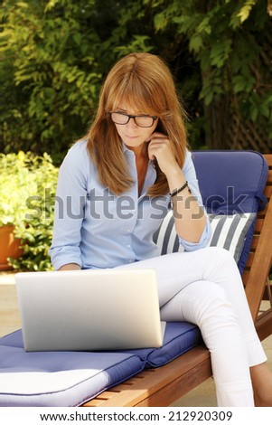 Modern businesswoman sitting at garden and working at home with laptop. Business people.