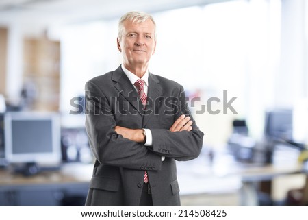 Portrait of executive senior businessman standing at office. Business people.