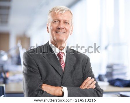 Portrait of executive senior businessman standing at office. Business people.