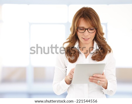 Portrait of middle age businesswoman standing with digital tablet at office. Business people.
