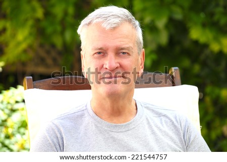 Portrait of modern grandfather sitting at garden at home.